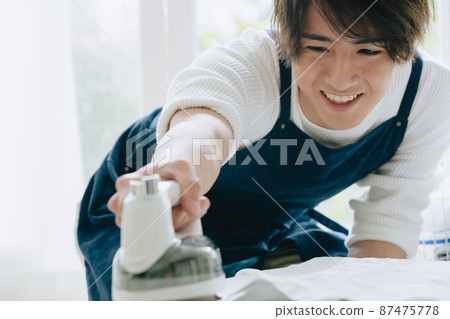 Young man ironing Young man ironing 87475778