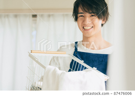 Young man cleaning up the laundry Young man cleaning up the laundry 87476006