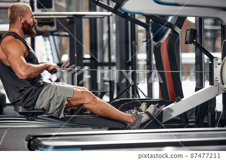 Training legs in the simulator, the athlete works with his legs on the simulator, working out the muscles on the legs 87477211