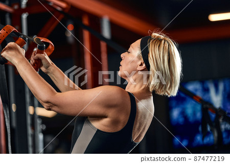 Women doing push ups training arms with trx fitness straps in the gym Concept workout healthy lifestyle sport 87477219