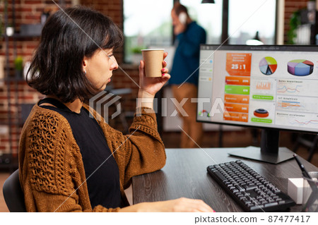Businesswoman looking at computer screen analyzing management graphs 87477417