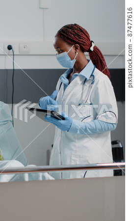 Woman working as doctor with tablet consulting ill patient 87477616