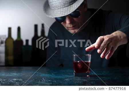 Man in the hat is drinking whiskey. Man in the hat is drinking whiskey. 87477916