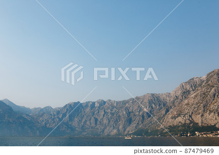 Kotor Bay surrounded by mountains in a light haze against a blue sky Kotor Bay surrounded by mountains in a light haze against a blue sky 87479469