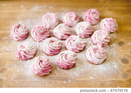 Pink marshmallow with powdered sugar lies on the table Pink marshmallow with powdered sugar lies on the table 87479576