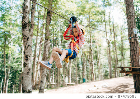 Boy goes down the zip line in the adventure park 87479595