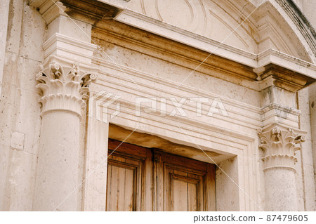 Central entrance with a wooden door to the Church of the Nativity of the Virgin in Prcanj 87479605