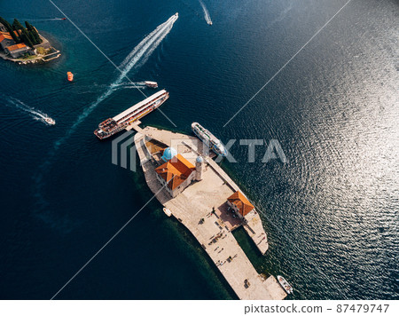 Boats moored near the island of Gospa od Skrpjela on the background of St. George island. Top view 87479747