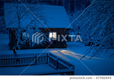 old house covered with snow in the evening 87480844