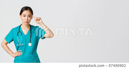 Covid-19, healthcare workers, pandemic concept. Annoyed skeptical asian female nurse or doctor scolding someone acting crazy or stupid, roll finger over temple with judgemental face Covid-19, healthcare workers, pandemic concept. Annoyed skeptical asian female nurse or doctor scolding someone acting crazy or stupid, roll finger over temple with judgemental face 87480902