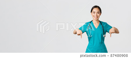 Covid-19, healthcare workers, pandemic concept. Smiling pleasant asian female doctor, therapist or physician in scrubs with stethoscope, pointing fingers down, show clinic banner Covid-19, healthcare workers, pandemic concept. Smiling pleasant asian female doctor, therapist or physician in scrubs with stethoscope, pointing fingers down, show clinic banner 87480908