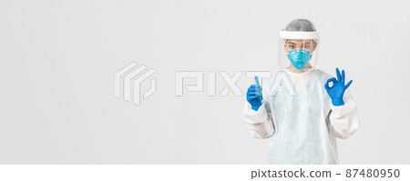 Covid-19, coronavirus disease, healthcare workers concept. Serious asian female doctor, professional researcher in personal protective equipment showing okay gesture, holding test-tube with vaccine Covid-19, coronavirus disease, healthcare workers concept. Serious asian female doctor, professional researcher in personal protective equipment showing okay gesture, holding test-tube with vaccine 87480950