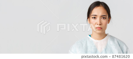 Covid-19, coronavirus disease, healthcare workers concept. Serious exhausted asian female doctor looking tired after shift at hospital, take-off personal protective equipment, have skin marks Covid-19, coronavirus disease, healthcare workers concept. Serious exhausted asian female doctor looking tired after shift at hospital, take-off personal protective equipment, have skin marks 87481620