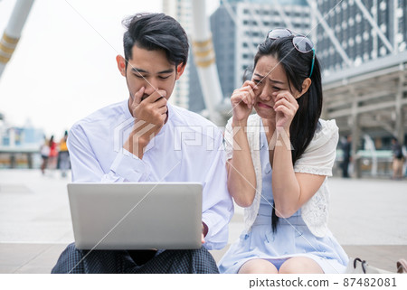 Couples are sit using laptop with sad about incident something in urban Couples are sit using laptop with sad about incident something in urban 87482081