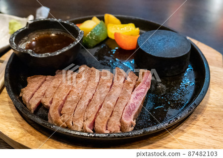 Beef medium rare steak sliced on hot stone pan 87482103