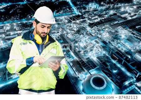 Caucasian technician engineer man using tablet checking the system on chemical refinery factory and building glowing in the night Caucasian technician engineer man using tablet checking the system on chemical refinery factory and building glowing in the night 87482113