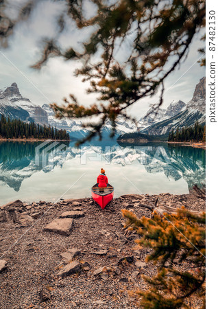 Female traveler in winter coat sitting on canoe in Spirit Island on Maligne Lake at Jasper national park Female traveler in winter coat sitting on canoe in Spirit Island on Maligne Lake at Jasper national park 87482130