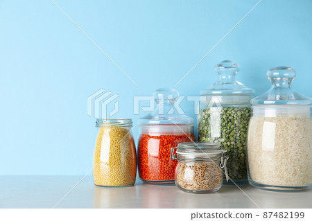 Glass jars with different types of groats on white wooden table 87482199