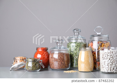 Jars with different cereals on grey table 87482202