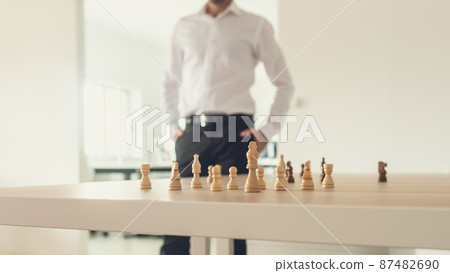 Retro image of a businessman standing proud next to his desk with chess figures on it Retro image of a businessman standing proud next to his desk with chess figures on it 87482690