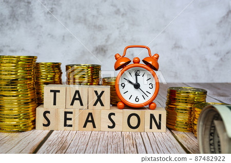 Text on wooden blocks and clock set at 10 o'clock with gold coins background. 87482922