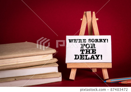 We're Sorry For The Delay. Miniature easel on a red background 87483472