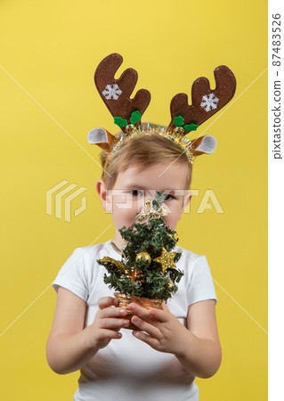 Happy funny child boy in red Christmas reindeer costume with christmas tree Happy funny child boy in red Christmas reindeer costume with christmas tree 87483526