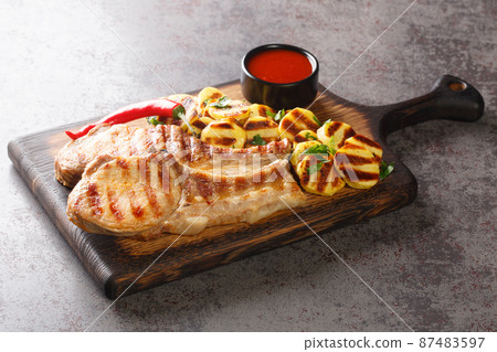 Homemade Barbecue Pork Chops and grilled potatoes Ready to Eat on a wooden board closeup. Horizontal 87483597
