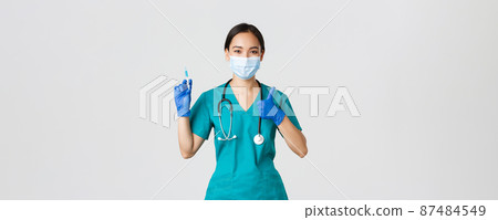 Covid-19, coronavirus disease, healthcare workers concept. Pleasant smiling asian female doctor, physician in medical mask and gloves, show thumb-up, hold syringe with vaccine Covid-19, coronavirus disease, healthcare workers concept. Pleasant smiling asian female doctor, physician in medical mask and gloves, show thumb-up, hold syringe with vaccine 87484549
