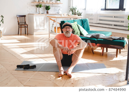 Senior man doing fitness exercises with virtual class and holding dumbbells - wellbeing and wellness concept Senior man doing fitness exercises with virtual class and holding dumbbells - wellbeing and wellness concept 87484990