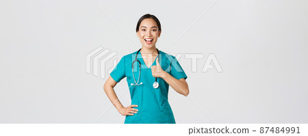 Covid-19, healthcare workers, pandemic concept. Smiling upbeat, confident female asian nurse in scrubs have all under control, show thumbs-up in approval, guarantee quality of service in clinic Covid-19, healthcare workers, pandemic concept. Smiling upbeat, confident female asian nurse in scrubs have all under control, show thumbs-up in approval, guarantee quality of service in clinic 87484991