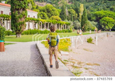 Boy tourist walking together in Montenegro. Panoramic summer landscape of the beautiful green Royal park Milocer on the shore of the the Adriatic Sea, Montenegro Boy tourist walking together in Montenegro. Panoramic summer landscape of the beautiful green Royal park Milocer on the shore of the the Adriatic Sea, Montenegro 87485769