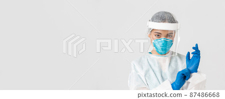 Covid-19, coronavirus disease, healthcare workers concept. Close-up of confident, professional female doctor put on personal protective equipment and rubber gloves to examine patient 87486668