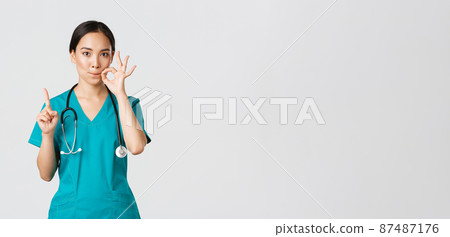 Covid-19, healthcare workers, pandemic concept. Serious-looking worried asian female nurse, physician asking keep secret, shaking finger and showing mouth seal, zipping lips gesture 87487176