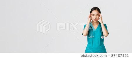 Covid-19, healthcare workers, pandemic concept. Overworked and tired young asian female nurse close eyes, grimacing from headache, feel dizzy, night shift with coronavirus patients, white background Covid-19, healthcare workers, pandemic concept. Overworked and tired young asian female nurse close eyes, grimacing from headache, feel dizzy, night shift with coronavirus patients, white background 87487361