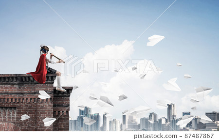 Girl power concept with cute kid guardian against cityscape background. Mixed media 87487867