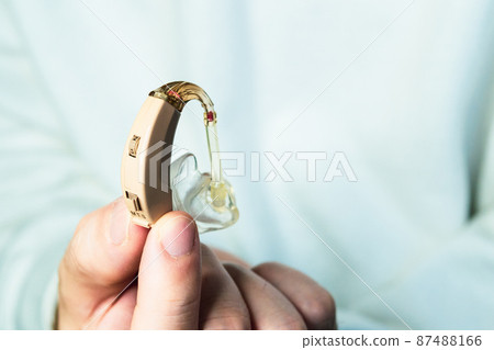 Male hand with flesh-colored hearing aid 87488166