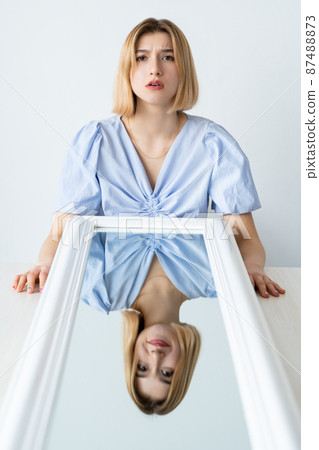 Panic attack. Bipolar disorder. Dual personality. Portrait of disturbed anxious worried scared woman with happy relaxed face mirror reflection isolated on white. Panic attack. Bipolar disorder. Dual personality. Portrait of disturbed anxious worried scared woman with happy relaxed face mirror reflection isolated on white. 87488873