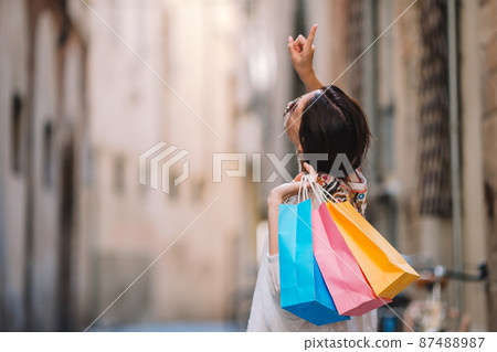 Young girl with shopping bags on narrow street in Europe. 87488987