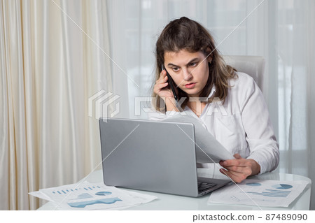 Disabled woman talks on phone looking at project paper 87489090