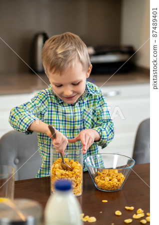Joyous child scooping ingredients for an oatmeal dish 87489401