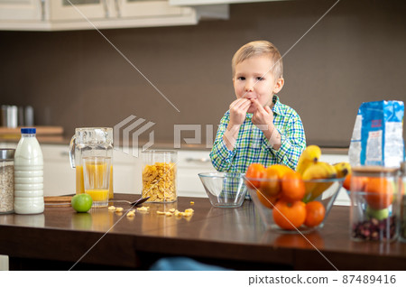 Hungry kid putting some food in his mouth 87489416