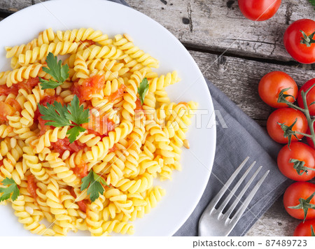 Pasta fusilli with tomatoes with parsley on a old rustic gray wooden background Pasta fusilli with tomatoes with parsley on a old rustic gray wooden background 87489723