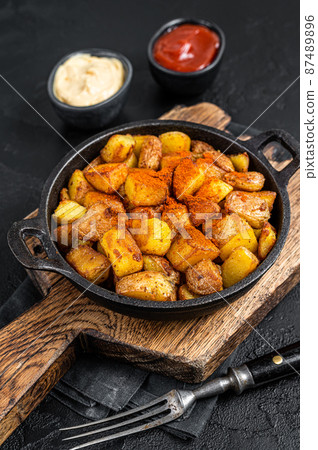 Patatas bravas, spicy potatoes, a Spanish dish with fried potato and a spicy garlic sauce. Black background. Top view Patatas bravas, spicy potatoes, a Spanish dish with fried potato and a spicy garlic sauce. Black background. Top view 87489896