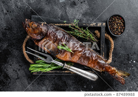 Hot smoked pike perch or zander fish in a wooden tray. Black background. Top view Hot smoked pike perch or zander fish in a wooden tray. Black background. Top view 87489988