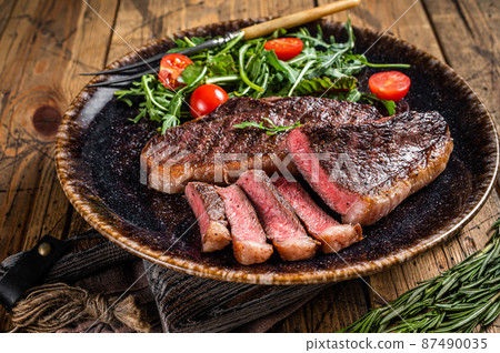BBQ Grilled cup rump beef meat steak in plate with vegetable salad. Wooden background. Top view 87490035