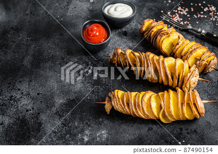 Roasted Tornado or twisted potatoes with ketchup sauce. Black background. Top view. Copy space Roasted Tornado or twisted potatoes with ketchup sauce. Black background. Top view. Copy space 87490154