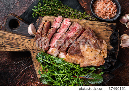 Grilled Chuck Roll beef steak with salad on wooden board. Dark background. Top view 87490161