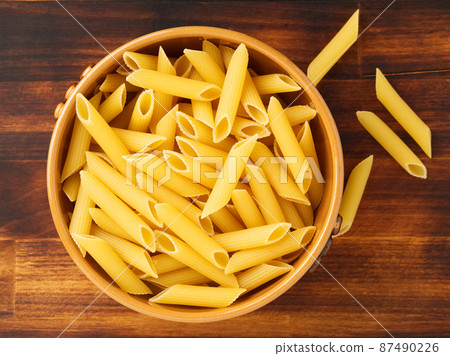 Pasta Tortiglioni in brown bowl on dark wooden brown table. Top view. 87490226
