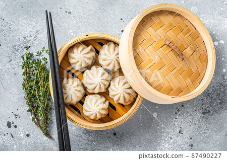 Steamed baozi dumplings stuffed with meat in a bamboo steamer. Gray background. Top view 87490227